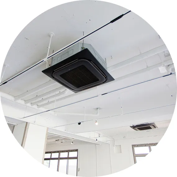 広い室内の天井に取り付けられた埋め込み型エアコンが見えるオフィス空間