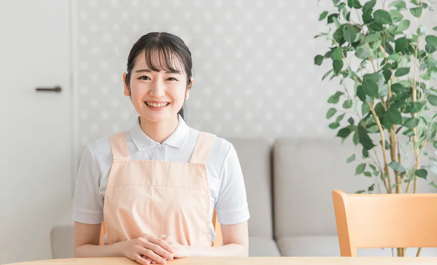 落ち着いたリビングで、笑顔を見せるエプロン姿の女性